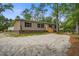 Inviting single-story home with tan siding, brick foundation, and a wooden porch, set in a spacious yard with mature trees at 413 Peacock Ln, Summerville, SC 29486