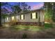Charming single-story home with updated siding, complemented by cozy outdoor lighting and a manicured landscape at twilight at 413 Peacock Ln, Summerville, SC 29486