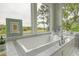 Bright bathroom with a soaking tub surrounded by windows offering stunning views of the lush landscape at 4874 Sound View Dr, Mount Pleasant, SC 29466