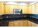 Kitchen featuring wooden cabinets, black granite countertops, stainless steel microwave, and black tiled backsplash at 5009 Old Bridgeview Ln # 5009, Charleston, SC 29403