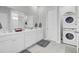 Spacious white bathroom with double vanity, marble floors, and stacked washer and dryer at 69 Arrowwood Way, Summerville, SC 29485