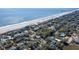 An aerial view featuring charming coastal homes nestled among trees, bordering the ocean and sandy beach at 716 E Arctic Ave, Folly Beach, SC 29439