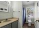Bathroom with a single sink vanity, toilet and shower with a blue patterned curtain at 716 E Arctic Ave, Folly Beach, SC 29439