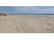 Expansive sandy beach with gentle waves rolling into the shoreline under a cloudy sky at 716 E Arctic Ave, Folly Beach, SC 29439