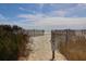 Beach access through dunes lined with weathered wooden fences leading to sandy shores at 716 E Arctic Ave, Folly Beach, SC 29439