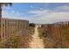 Sandy path leading to a serene beach framed by wooden fencing and lush vegetation at 716 E Arctic Ave, Folly Beach, SC 29439