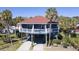 Charming raised beach house with a red roof, blue siding, and beautiful tropical landscaping at 716 E Arctic Ave, Folly Beach, SC 29439