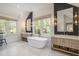 Luxurious bathroom with soaking tub, dual vanities, modern fixtures, dark accent wall and large windows at 750 Atlantic St, Mount Pleasant, SC 29464