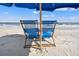 Reserved beach chairs under a blue umbrella offer a relaxing spot to enjoy ocean views and sandy shores at 9000 Palmetto Dr # G203, Isle of Palms, SC 29451