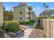Exterior view of condos with multiple balconies, surrounded by lush landscaping and a wooden walkway at 9000 Palmetto Dr # G203, Isle of Palms, SC 29451