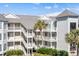 Multi-level condo building with private balconies and staircases surrounded by tropical foliage and lush landscaping at 9000 Palmetto Dr # G203, Isle of Palms, SC 29451