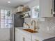 Modern kitchen with white cabinets, gold faucet, mosaic backsplash, and stainless steel refrigerator at 10 Humphrey Ct, Charleston, SC 29403