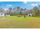 Expansive backyard with lush green grass, mature trees, and storage sheds, offering ample space for outdoor activities at 1644 Cooper Store Rd, Moncks Corner, SC 29461
