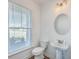 Powder room with a pedestal sink, round mirror, and natural light from the window at 175 Darby Meadow Ln, Ridgeville, SC 29472