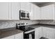 Modern kitchen featuring white cabinets, stainless steel appliances, granite countertops, and a stylish tile backsplash at 2150 Pimlico Dr, Ridgeville, SC 29472