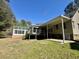 View of the backyard with a sunroom, wooden deck, patio, and lush green grass at 2164 Highway 78, Dorchester, SC 29437