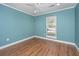 A bedroom with beautiful blue walls and hardwood floors, with a window letting in natural light at 2306 Chairmaker Ct, Charleston, SC 29414