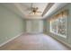 Main bedroom with tray ceiling, ceiling fan, carpet, and a large window overlooking a yard at 329 Carriage Wheel Rd, Moncks Corner, SC 29461