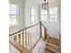 Staircase landing with hardwood and white railings, lit by a modern chandelier, and brightened by three windows at 3889 Summerton St, Mount Pleasant, SC 29466