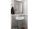 Cozy powder room with a pedestal sink, decorative mirror, and neutral tones at 546 Alderly Dr, Moncks Corner, SC 29461