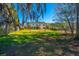Large, grassy backyard with a two-story home, mature trees, and a black metal fence at 9408 Harroway Rd, Summerville, SC 29485