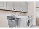 Well-equipped laundry room featuring front loading washer/dryer, stainless steel sink, and white cabinets at 105 Bluff Isle Ct, Summerville, SC 29486