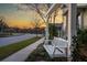 White porch swing in front of home with manicured lawn during a colorful sunset at 107 Nutmeg Way, Summerville, SC 29485