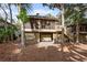 Back exterior of the home with a screened porch, stairs, and lush greenery at 1153 Summerwind Ln, Seabrook Island, SC 29455