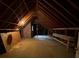 Unfinished attic space with exposed beams and a small window at 116 W Johnston St, Summerville, SC 29483