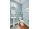Stylish half bath with pedestal sink, oval mirror, and modern fixtures on hardwood floor at 1807 Chauncy'S Ct, Mount Pleasant, SC 29466