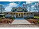 Inviting two-story home boasts a spacious wraparound porch, enhanced by lush landscaping and a concrete driveway at 212 Chester Ln, Cottageville, SC 29435