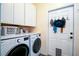 Functional laundry room with a washer, dryer, storage cabinets, and convenient hooks for hanging clothes and accessories at 212 Chester Ln, Cottageville, SC 29435