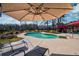 Relaxing poolside area featuring lounge chairs under a large shade umbrella at 212 Chester Ln, Cottageville, SC 29435