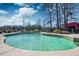 Swimming pool surrounded by shrubs and concrete, near a red pool house at 212 Chester Ln, Cottageville, SC 29435
