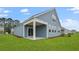 View of light-blue home with a covered patio, multiple windows, and a well-manicured green lawn at 2196 Macallan Blvd, Ravenel, SC 29470