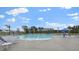 Resort-style pool area featuring blue lounge chairs, umbrellas, and palm trees, all under a clear sky at 2196 Macallan Blvd, Ravenel, SC 29470