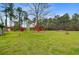 Large backyard with mature trees featuring a detached red outbuilding, offering ample outdoor space at 276 S Railroad Ave, Harleyville, SC 29448