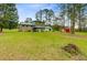 View of the backyard showcasing the home's exterior and spacious green lawn with outbuildings at 276 S Railroad Ave, Harleyville, SC 29448