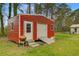 Exterior view of a red storage shed with a roll-up door and a grill outside at 276 S Railroad Ave, Harleyville, SC 29448