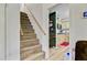 Carpeted staircase leading to an upstairs area with access to a kitchen with light wood cabinets at 276 S Railroad Ave, Harleyville, SC 29448