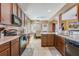 Open-concept kitchen with wooden cabinets, tile backsplash, and stainless steel appliances overlooking dining area at 3016 Adventure Way, Ladson, SC 29456