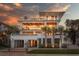 Elegant three-story home with a gated entrance, lush landscaping, and ample parking space at 3803 Palm Blvd, Isle of Palms, SC 29451