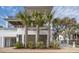 Elegant three-story home with sleek modern design, complemented by tropical landscaping and palm trees at 3803 Palm Blvd, Isle of Palms, SC 29451