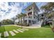 Well-manicured front yard with lush grass, palm trees, brick-paved walkway, and multi-story home at 3803 Palm Blvd, Isle of Palms, SC 29451