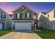 Inviting two-story home featuring a two-car garage, stone accents, and manicured lawn at dusk at 458 Whispering Breeze Ln, Summerville, SC 29486
