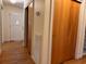 Hallway view showcasing wood-paneled closet doors, hardwood floors, and a bright white front door at 5310 Edith St, North Charleston, SC 29418