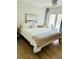 Bedroom featuring a queen bed, white bedding, a sliding door with blue chairs, and light hardwood floors at 60 Fairway Dunes Ln, Isle of Palms, SC 29451
