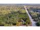 Aerial view of a home outlined in red on a wooded lot with a busy road nearby and surrounded by lush, mature trees at 10812 Dorchester Rd, Summerville, SC 29485