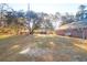 Large grassy backyard with mature trees and a view of the brick home's side and additional structures at 10812 Dorchester Rd, Summerville, SC 29485