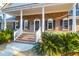 Inviting brick home with a classic front porch, white columns, and well-manicured landscaping at 10812 Dorchester Rd, Summerville, SC 29485